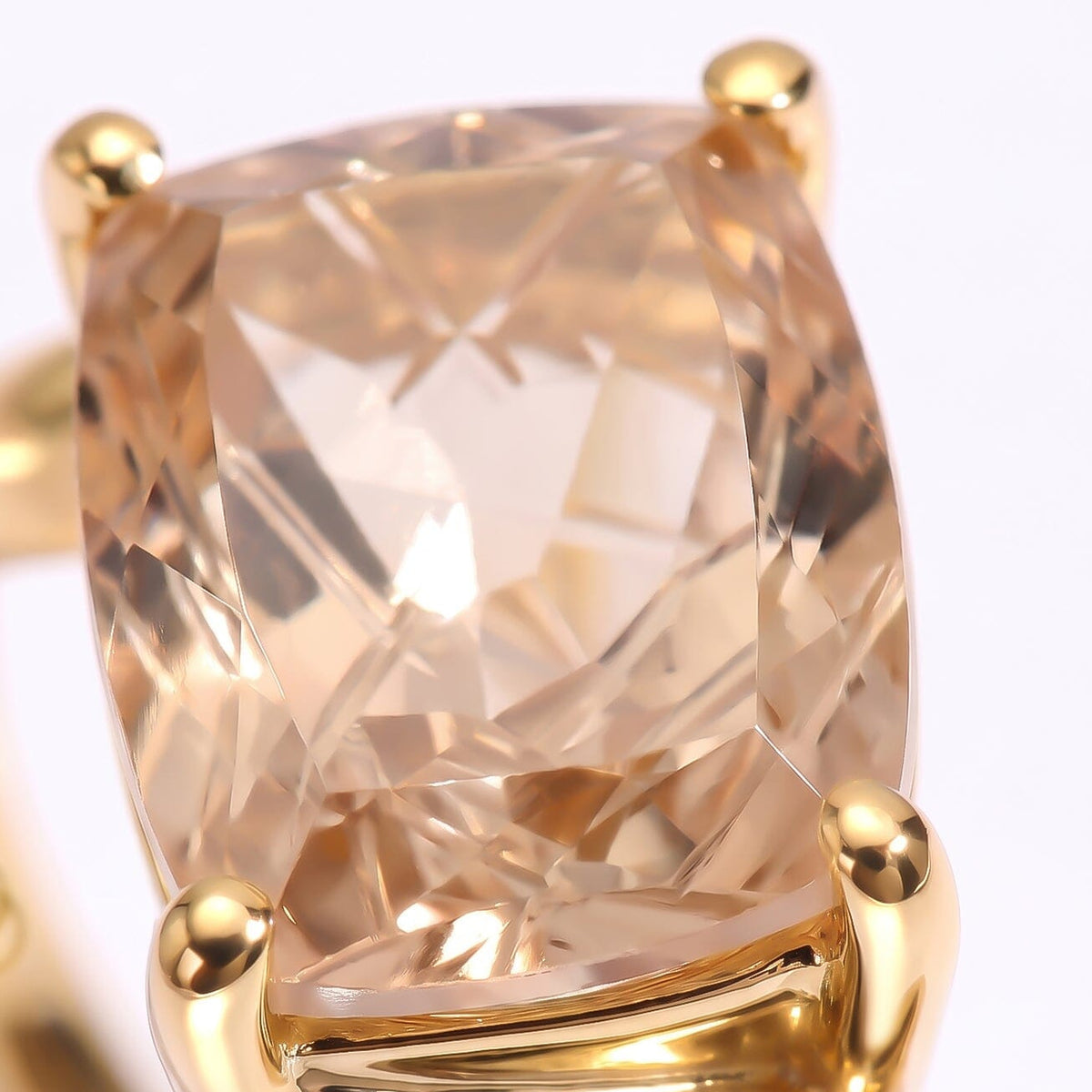 A close view reveals intersecting carved facets in champagne quartz held by rounded gold prongs.