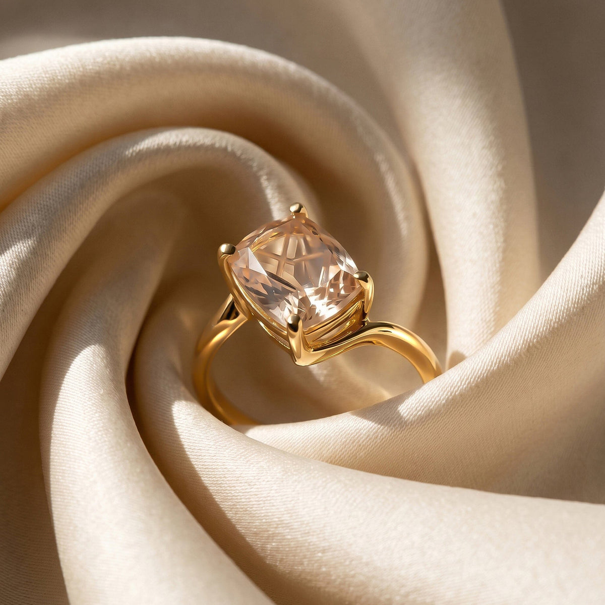 The gold ring rests between smooth folds of pale fabric with its tilted quartz facing the light.