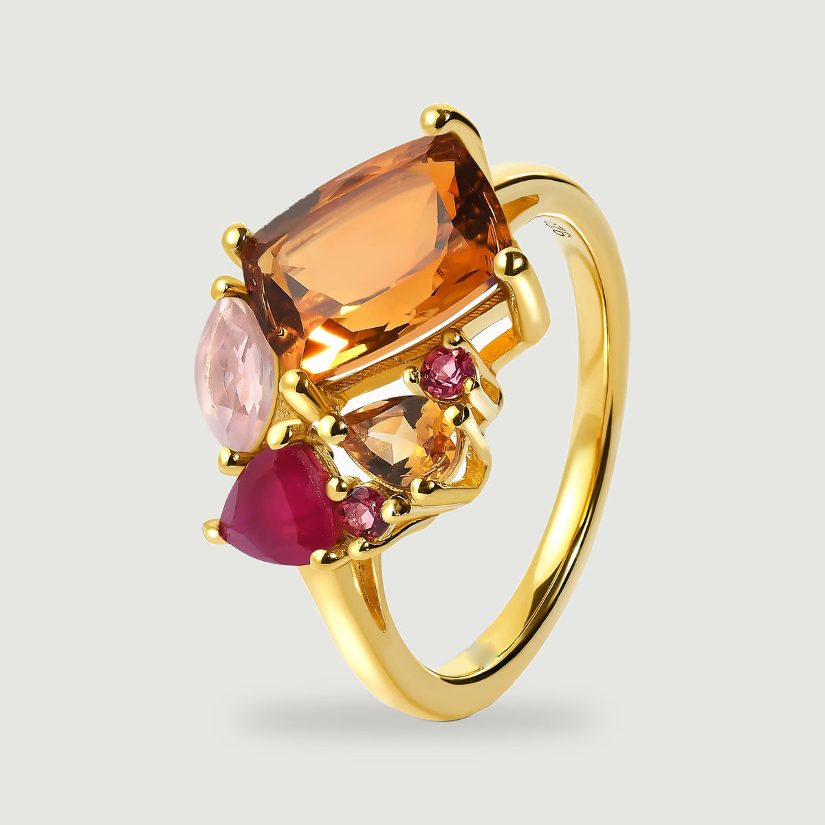 The ring stands at an angle showing its slim yellow gold band and raised multicolored gemstone settings.