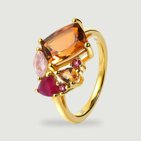 The ring stands at an angle showing its slim yellow gold band and raised multicolored gemstone settings.