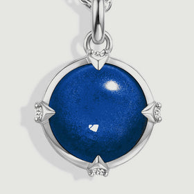 The domed blue cabochon is shown close up with four small clear accents and a polished silver rim.