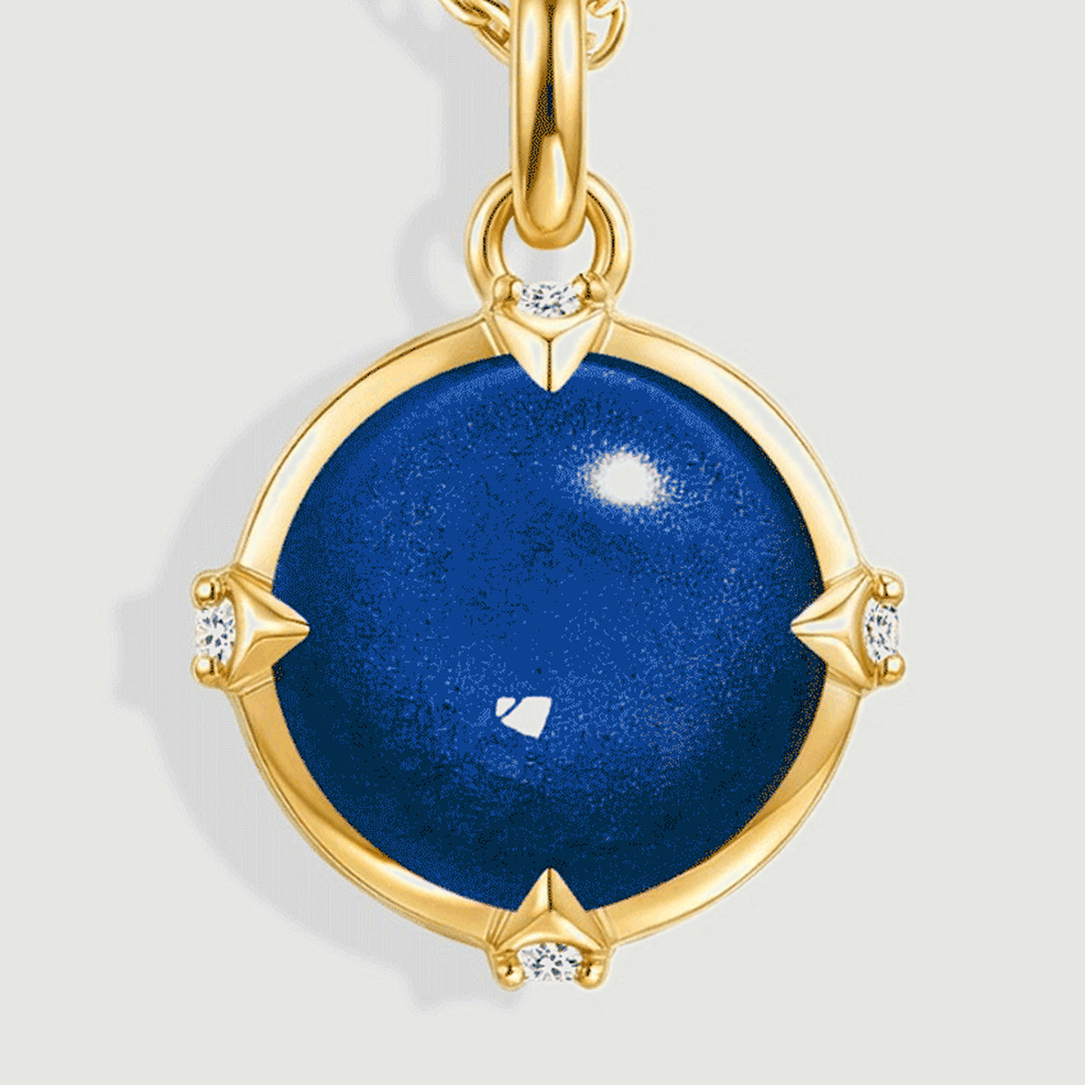 The domed blue cabochon is shown close up with four small clear accents and a polished yellow gold rim.