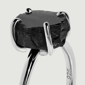 A close view shows the uneven black obsidian surface and silver prongs above the slim silver band.
