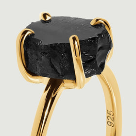 Yellow gold vermeil prongs curl around the rough edges of a black obsidian stone in a close view of the setting.