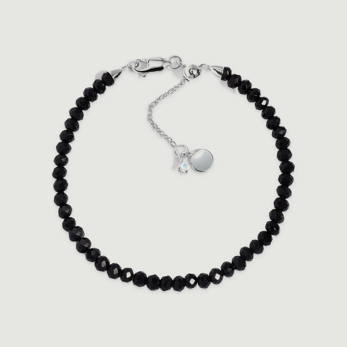 A complete black obsidian bead bracelet has a sterling silver clasp and extender on a light gray background.