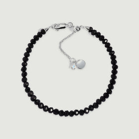 A complete black obsidian bead bracelet has a sterling silver clasp and extender on a light gray background.