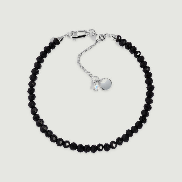 A complete black obsidian bead bracelet has a sterling silver clasp and extender on a light gray background.