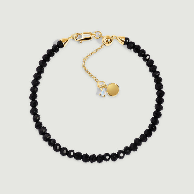 Faceted black obsidian beads form a circle with yellow gold vermeil fastenings and a small round charm.