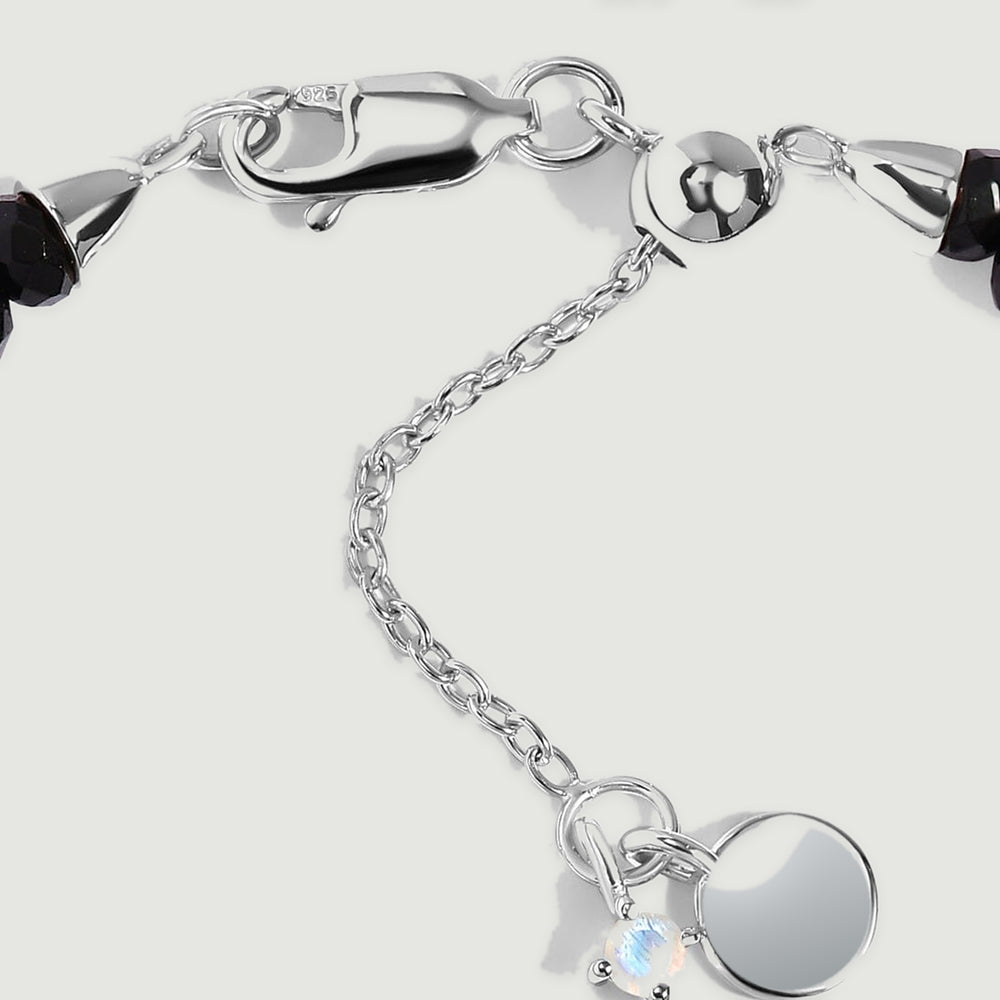 The sterling silver lobster clasp, fine extender chain, and dark faceted beads are shown in close detail.