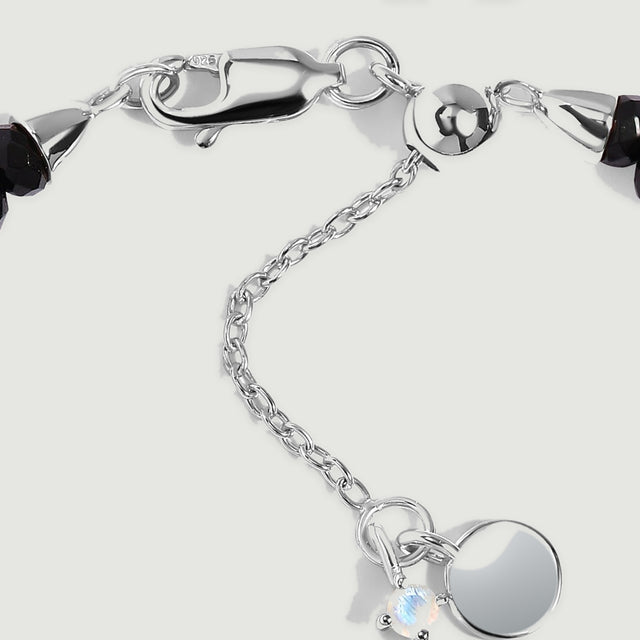 The sterling silver lobster clasp, fine extender chain, and dark faceted beads are shown in close detail.