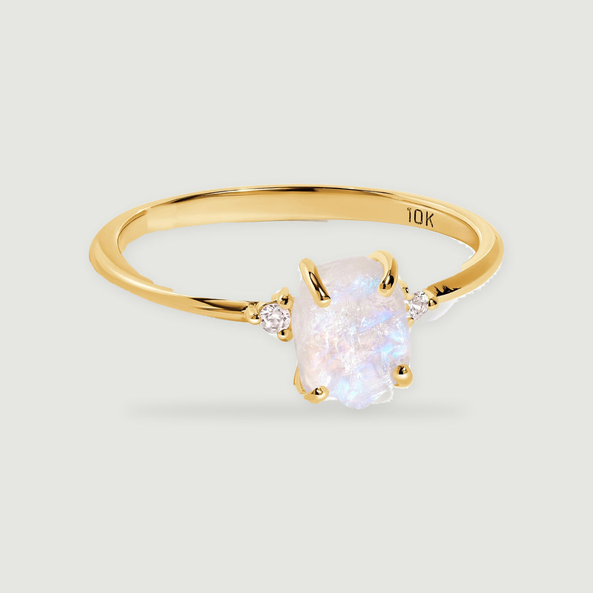 A yellow gold ring holds a rough white moonstone between two small round diamond accents.