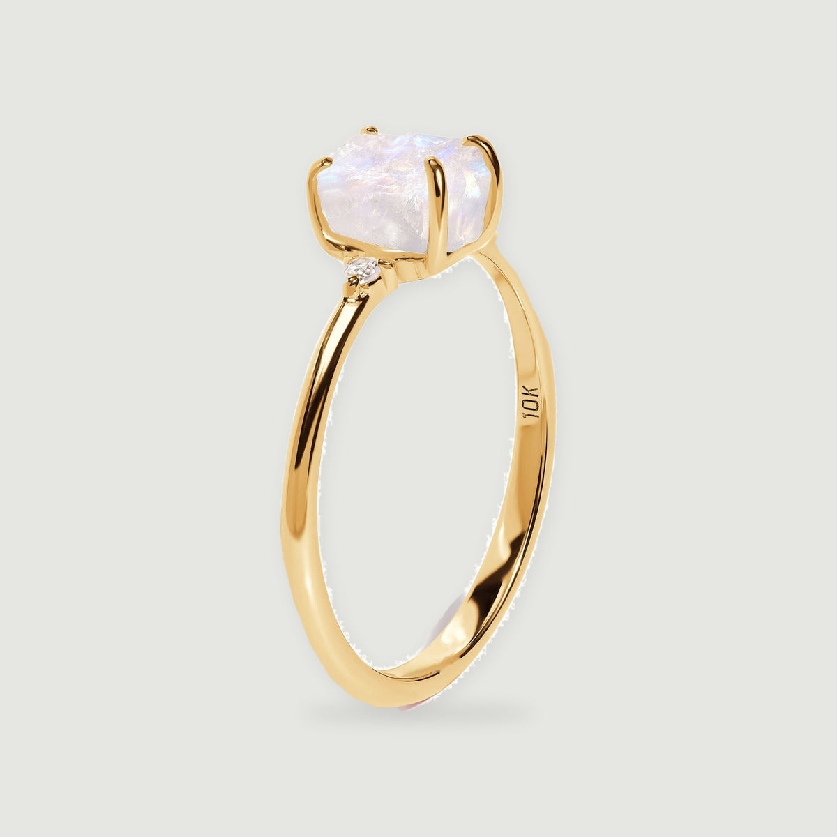 The side of a yellow gold ring reveals its raised moonstone setting and slim polished band.