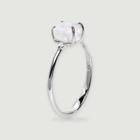 A white gold ring is viewed from the side with a rough crystal above the curved band.