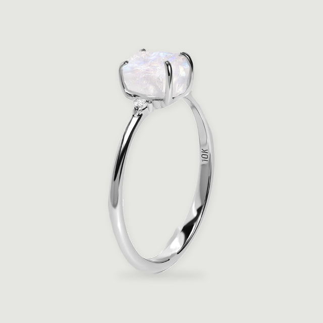 A white gold ring is viewed from the side with a rough crystal above the curved band.