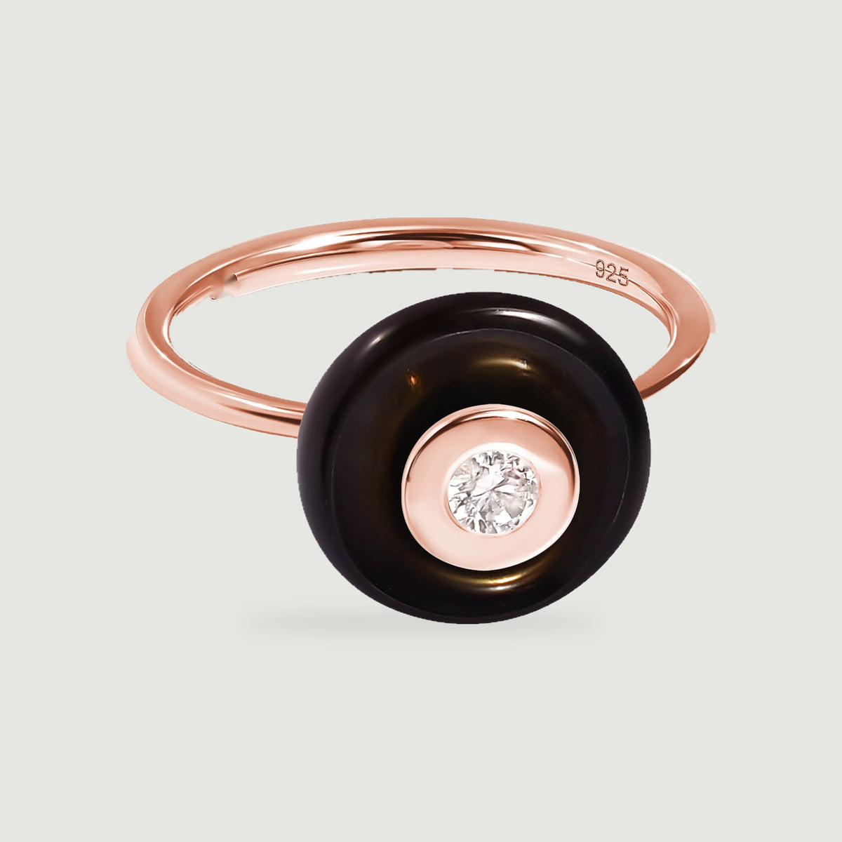 A rose gold band and round center setting frame the polished black stone on a pale gray background.