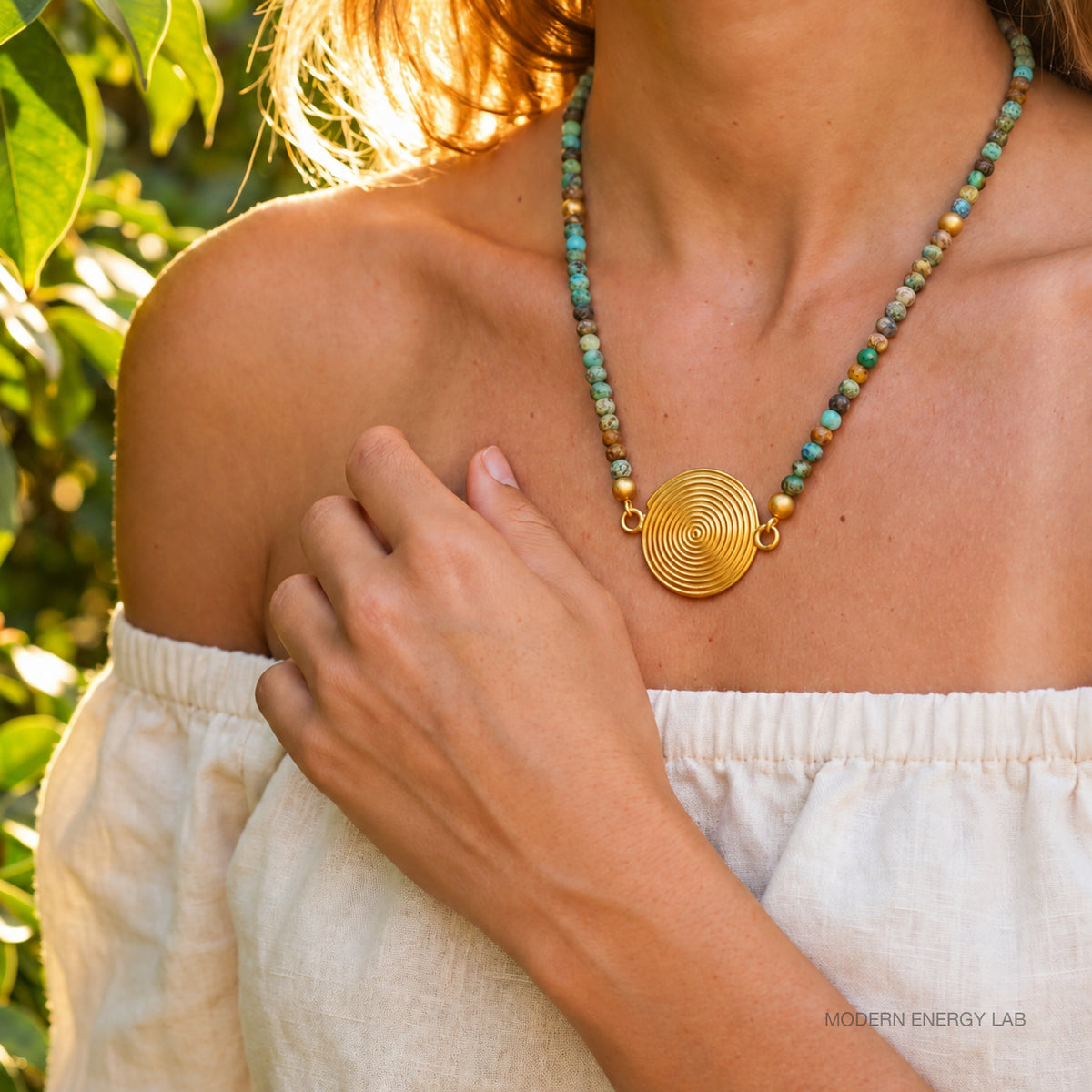 Turquoise spiral pendant necklace worn with an ivory blouse outdoors