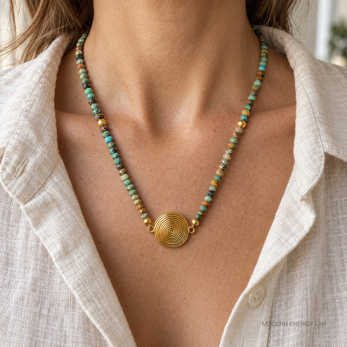 Faceted turquoise spiral pendant necklace worn with a cream linen shirt