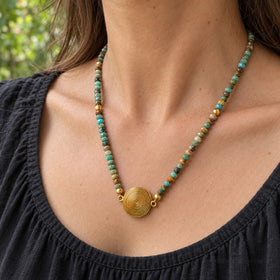Faceted turquoise spiral pendant necklace worn with a charcoal top in a garden