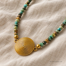New angled close view of the spiral pendant and faceted turquoise beads on ivory linen