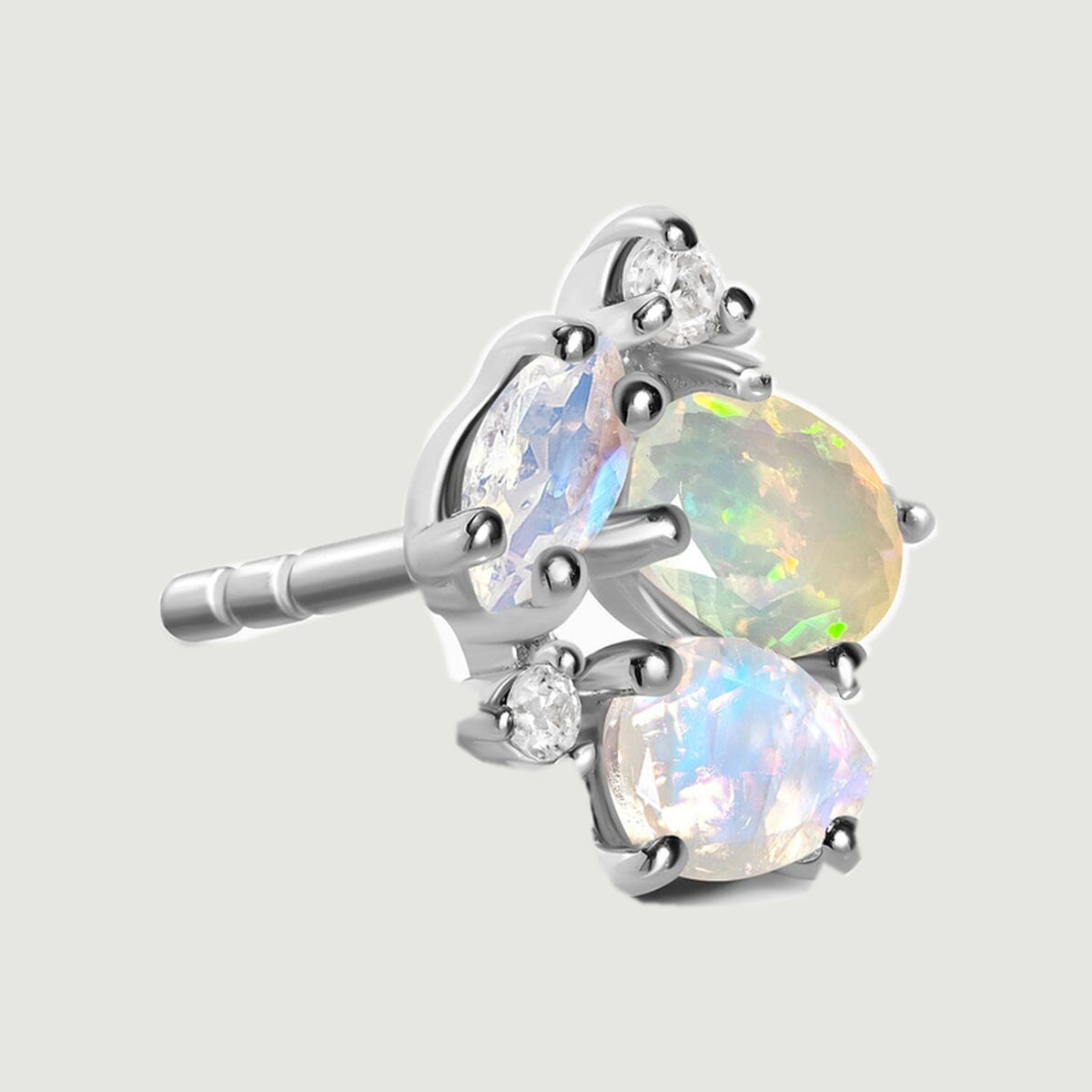 The side of a silver cluster stud reveals its straight post and raised gemstone settings against light gray.