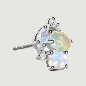 The side of a silver cluster stud reveals its straight post and raised gemstone settings against light gray.