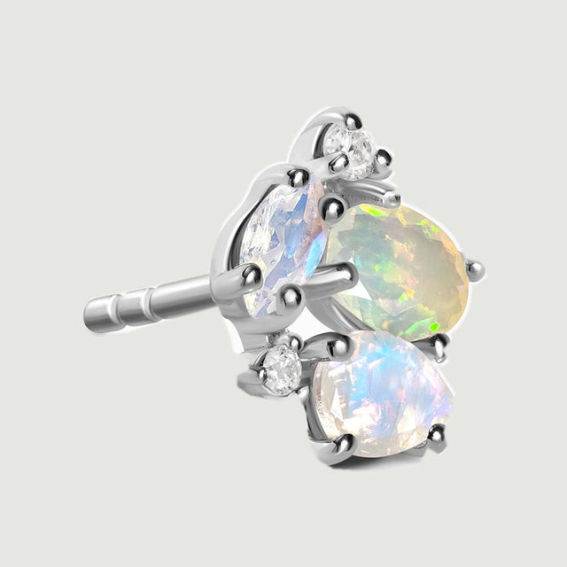 The side of a silver cluster stud reveals its straight post and raised gemstone settings against light gray.