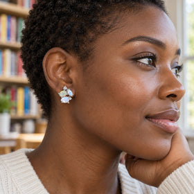 A woman with short natural hair wears a silver opal and moonstone stud in front of softly blurred library shelves.