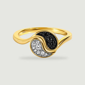 A yellow gold ring with curved sections of black and clear stones rests on a light gray surface.