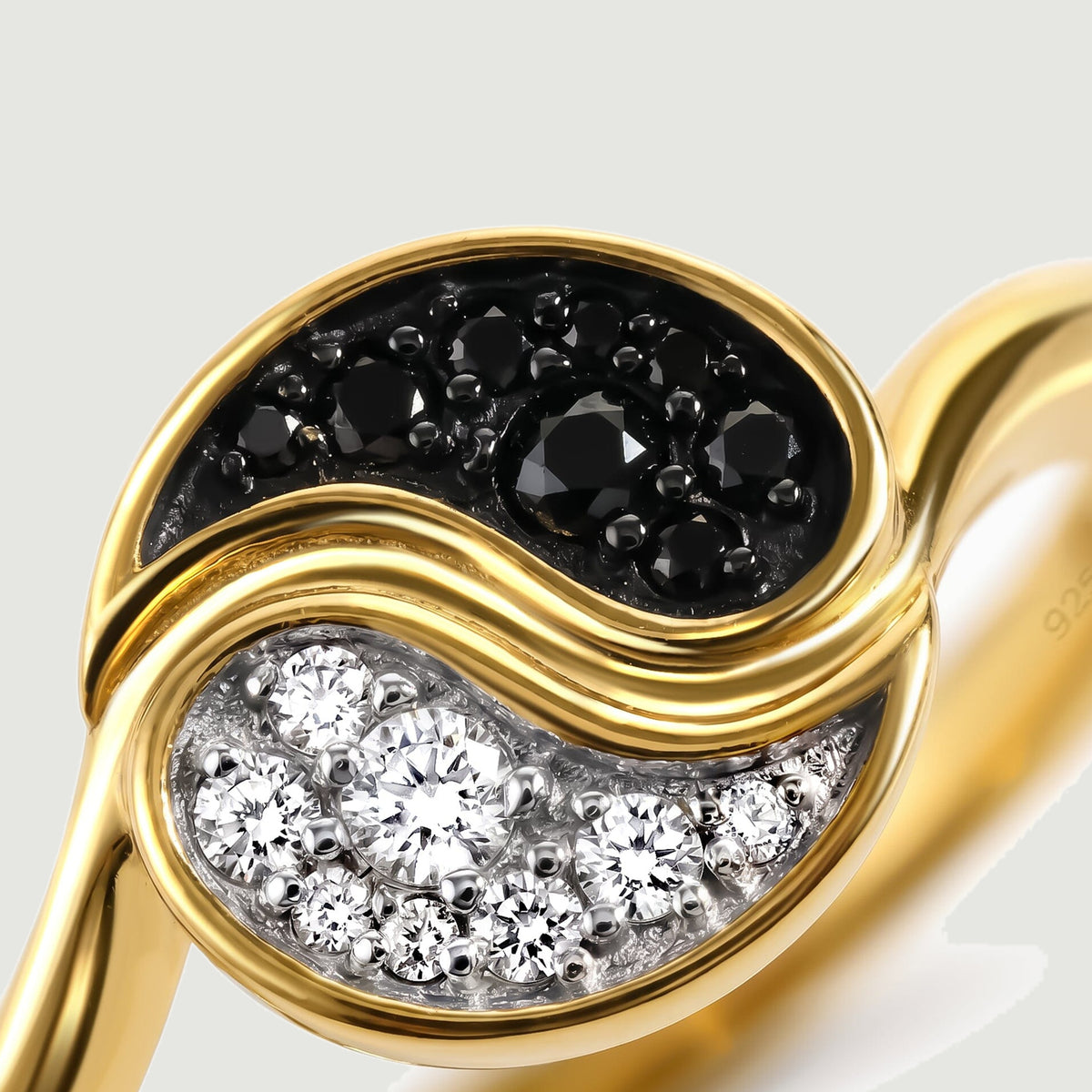 A close view shows black faceted stones and clear stones separated by a polished yellow gold curve.