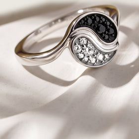 A silver ring casts a curved shadow across a pale textured surface in natural light.