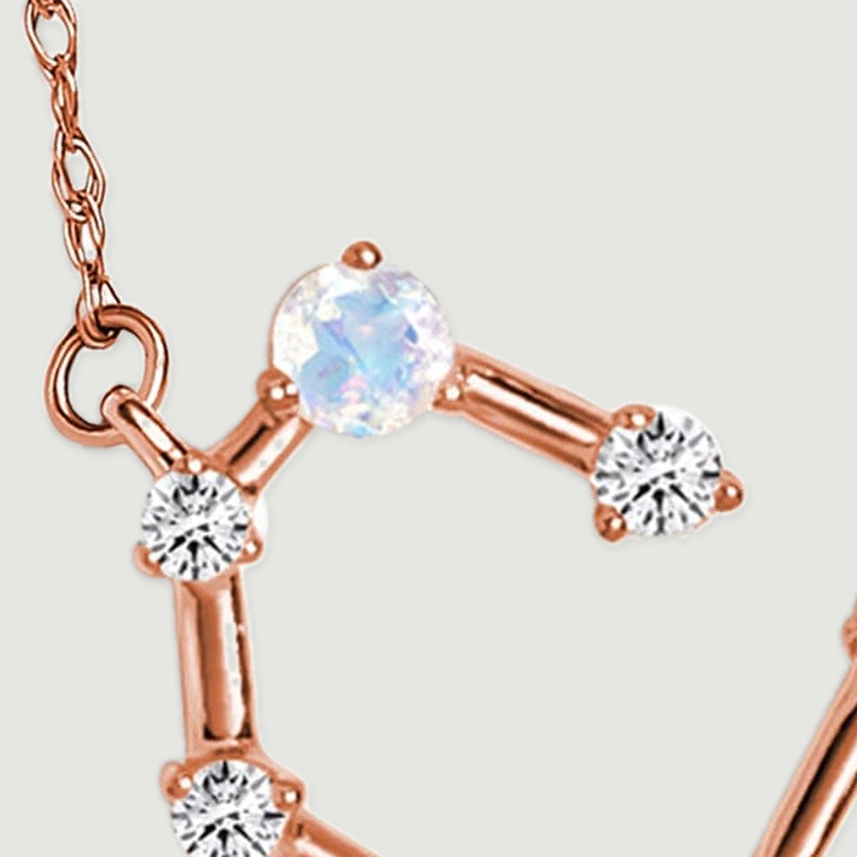 The left chain attachment leads to a moonstone and three diamond accents on rose gold links.