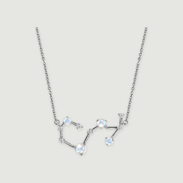 A silver necklace displays a curved constellation pendant with blue-white stones and small clear accents.