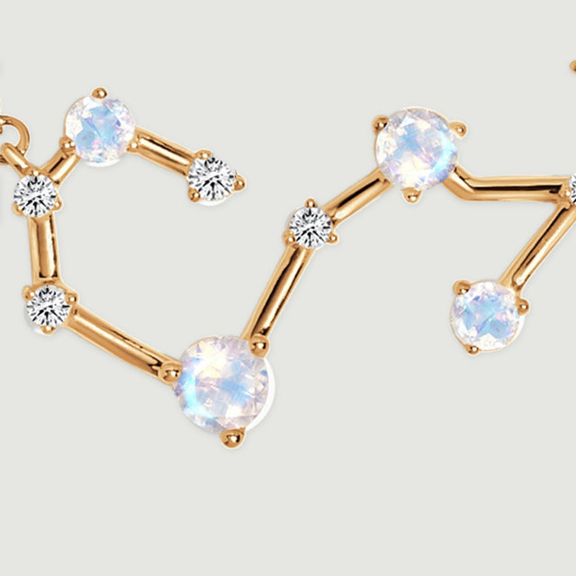 A close view of the yellow gold pendant shows round luminous stones linked by curved polished bars.