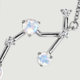 A close view of the silver pendant reveals a pale round stone, clear accents, and branching metal bars.
