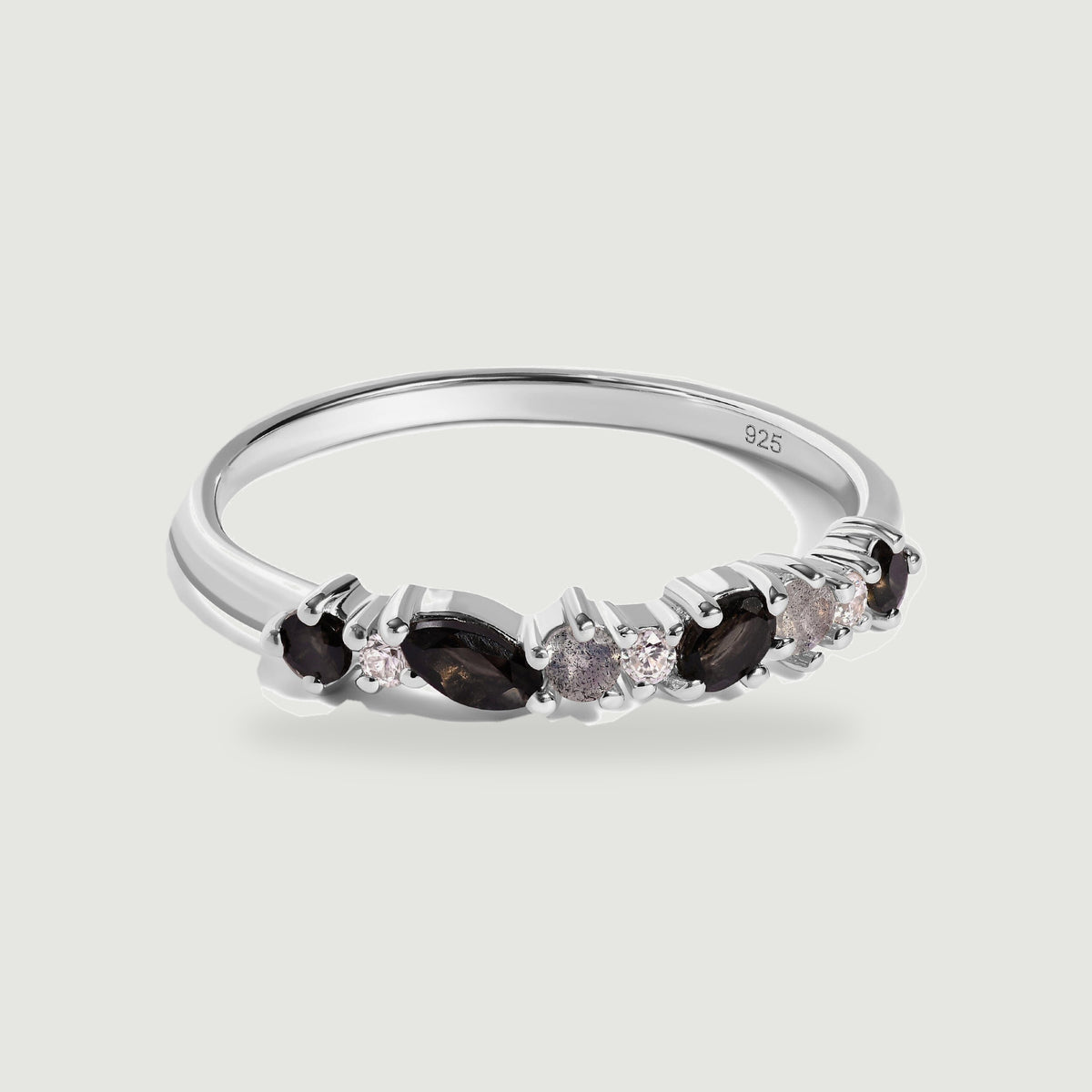 A sterling silver ring with black marquise stones and smaller round stones rests on a pale gray background.