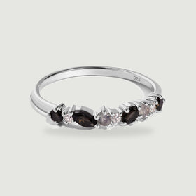 A sterling silver ring with black marquise stones and smaller round stones rests on a pale gray background.