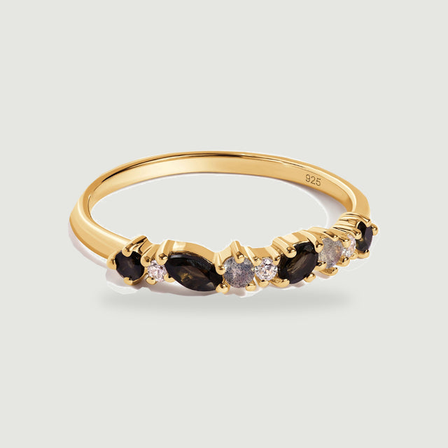 A yellow gold vermeil ring with black marquise stones and smaller round stones rests on a pale gray background.