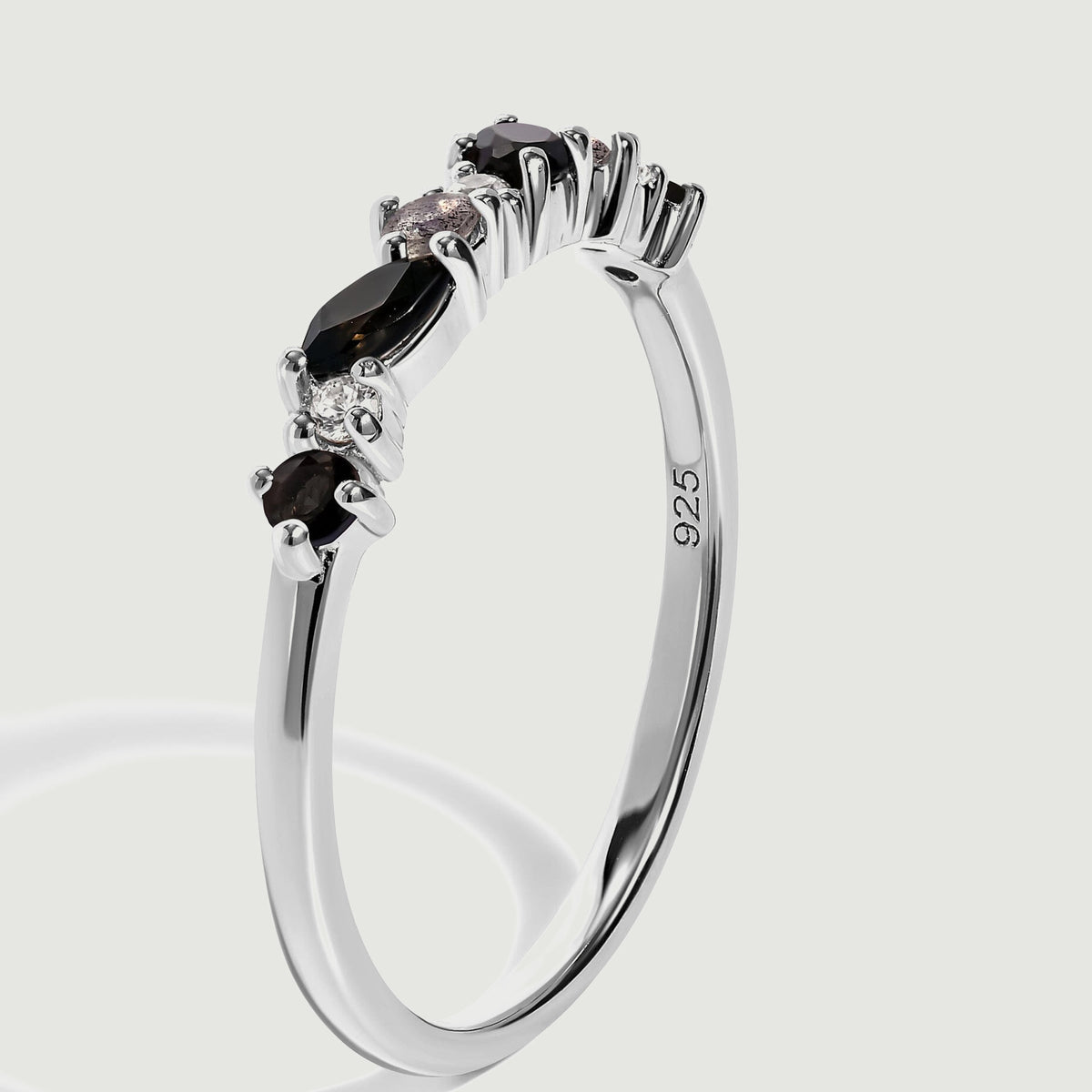 The silver ring is shown upright at an angle, revealing raised prong settings and the inside of the band.