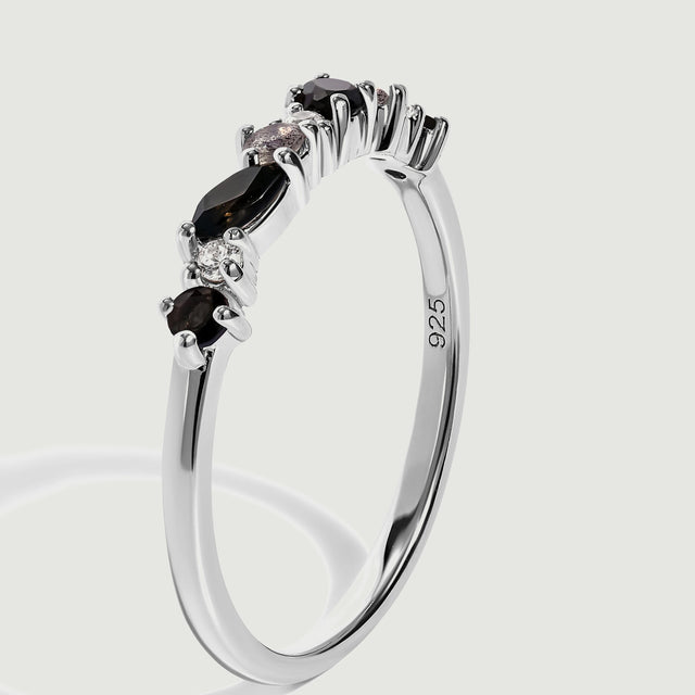 The silver ring is shown upright at an angle, revealing raised prong settings and the inside of the band.