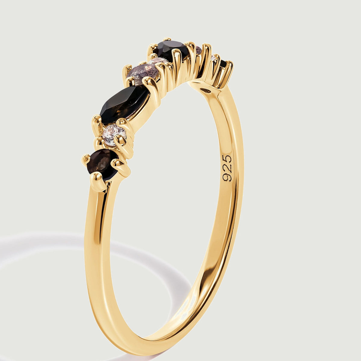 The gold-colored ring is shown upright at an angle, revealing raised prong settings and the inside of the band.