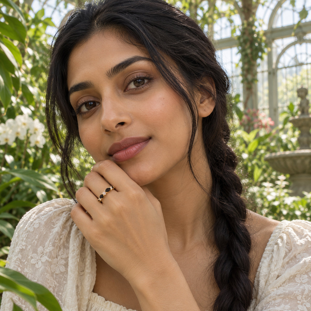 A woman with braided dark hair wears the yellow gold vermeil ring with her hand raised near her chin in a leafy greenhouse.
