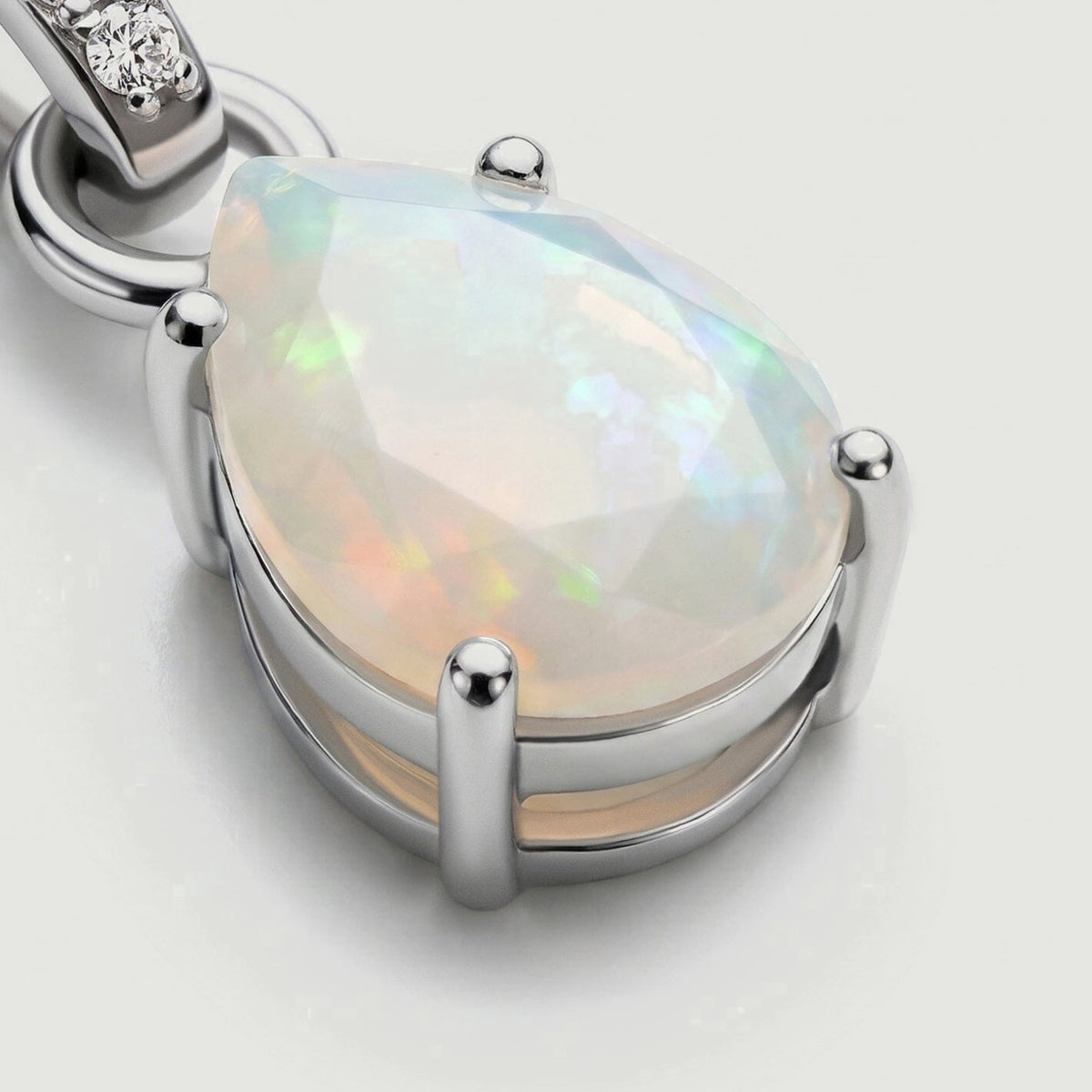A close view reveals pale opal facets, rounded silver prongs and the open rail beneath the stone.