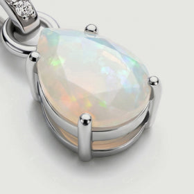 A close view reveals pale opal facets, rounded silver prongs and the open rail beneath the stone.