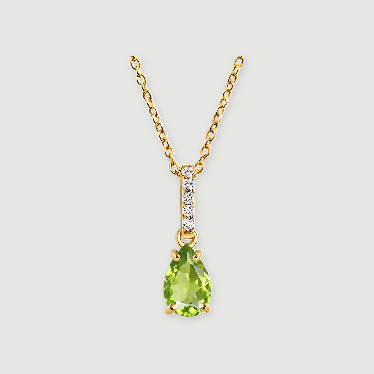A pear-shaped green peridot hangs below a white-stone bail on a yellow gold vermeil chain against a light gray background.