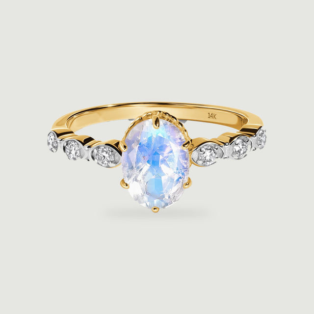 A yellow gold band holds an oval moonstone above six bright round diamond accents.
