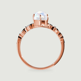 The side of a rose gold ring shows the raised moonstone setting and curved polished band.