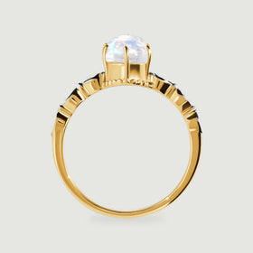 The yellow gold ring profile reveals slender prongs and diamond set shoulders around the oval stone.