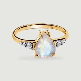 A yellow gold ring has a pear-shaped moonstone and three round diamonds on each shoulder.