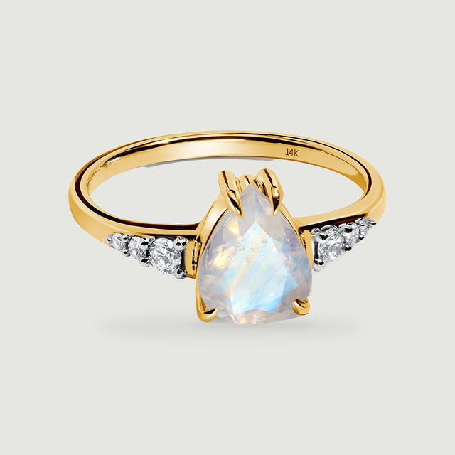 A yellow gold ring has a pear-shaped moonstone and three round diamonds on each shoulder.