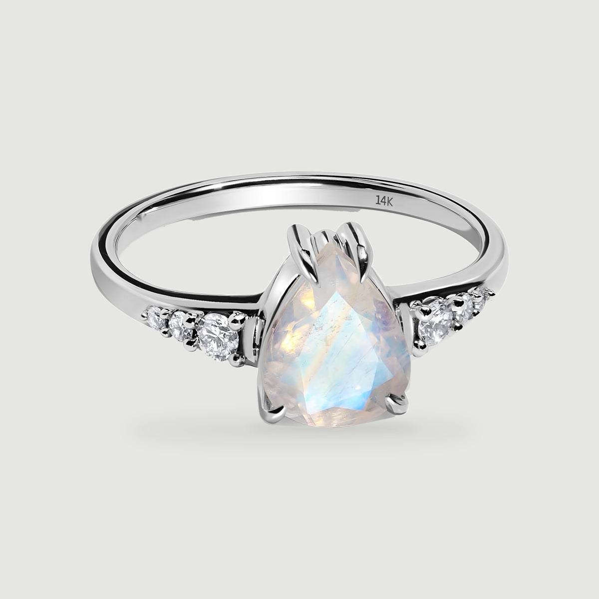 A polished white gold band surrounds a faceted pear-shaped moonstone with diamond accents.